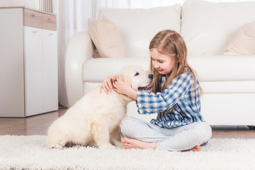 Smiling little girl sitting with fluffy retriever puppy at home