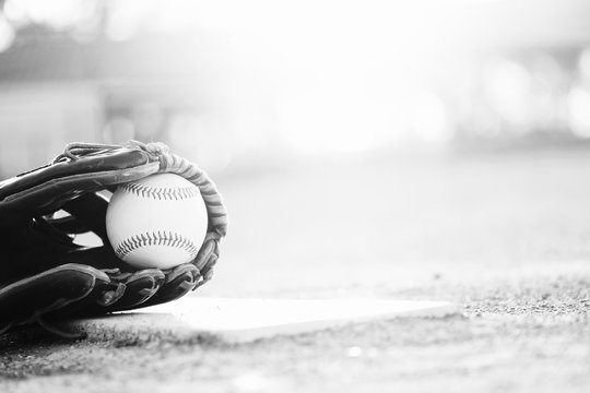 baseball and glove on ball field in black and white with copy space for sports seasno.