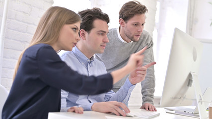 Young People Discussing and Working on Desktop
