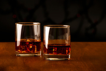 Whiskey with ice or brandy in a glass on a rustic background. Whiskey with ice in a glass. Whiskey or brandy. Selective focus.