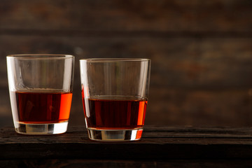 Whiskey with ice or brandy in a glass on a rustic background. Whiskey with ice in a glass. Whiskey or brandy. Selective focus.