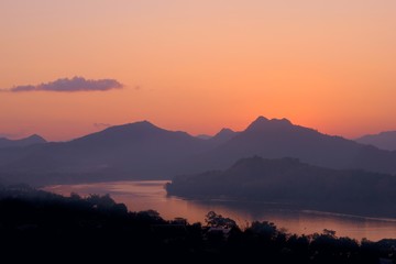 Twilight colors over hazy mountains by the Mekong river. View from Mount Phou Si, in Luang Prabang,...