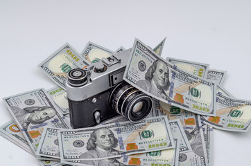 Vintage film camera on scattered American dollars. Concept of earning on photo stocks.