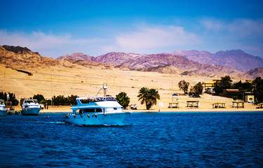 Luxury yacht going into deep blue sea from idyllic sand beach