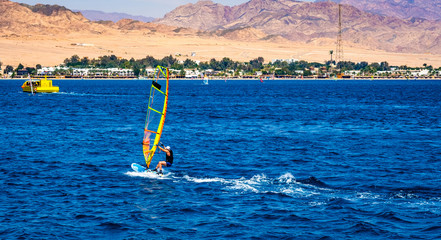 Man with extreme windsurfing sport in blue sea with sand beach on background