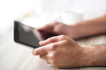Male hands holding and using tablet computer