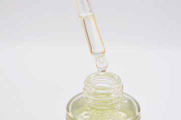 drops of collagen serum moisturizer face in a transparent yellow bottle soft light background. Skin Protector Facial Treatment Essential Oil, Vitamin C. Beauty and Spa Concept.