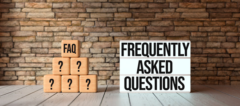 cubes with the abbreviation FAQ and lightbox with message FREQUENTLY ASKED QUESTIONS in front of a brick wall on wooden floor