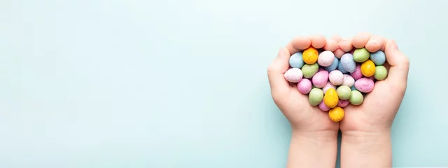 Foto op Plexiglas Child hands with Easter candies on blue background. © Olga Zarytska