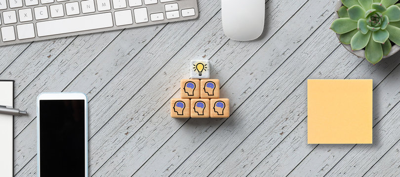 cubes with person-symbols stacked as a pyramid with office items on wooden background