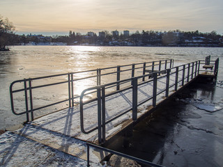 pier on icy lake in winter