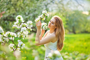 Beautiful teen redhead girl enjoying life in spring blossoming garden against blooming trees. Young dreamy thoughtful lady in nature at sunset. Springtime at countryside concept