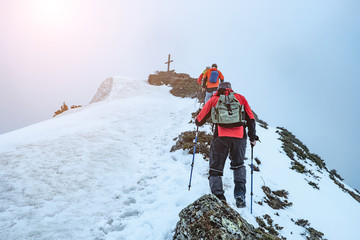 Line of hikers are climbing towards top of the mountain, covered in thick fog
