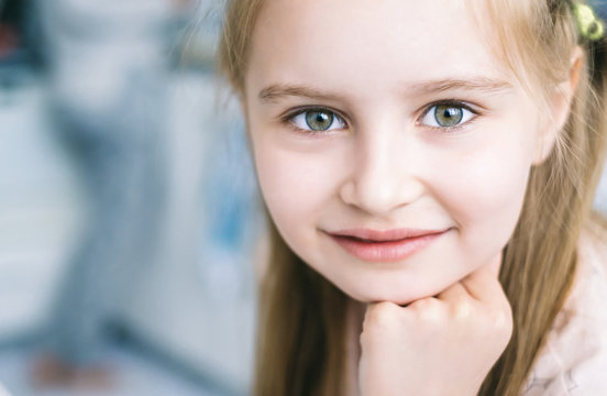 Closeup of cute smoling girl with green eyes looking in camera