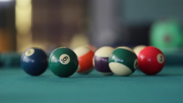 Close up at eye level of the cue ball hitting the apex ball on a green billiard table