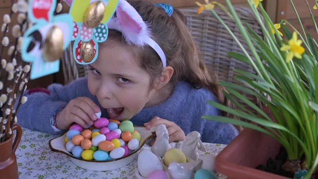 Easter. Little girl with colored eggs and chocolate colored eggs. Happy Easter holiday at home. Girl has fun and plays with eggs.