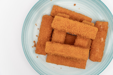 Fried fish sticks on the plate above white background