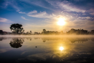 Reflection of the first rays of the sun in a misty lake