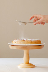 Homemade tender charlotte (apple pie) sprinkled with powdered sugar on a wooden stand.