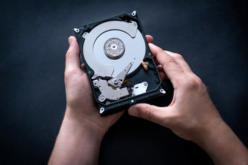 Repairman holding hard drive from computer in hands for fixing or diagnostics, top view