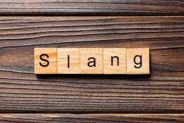 Fotobehang slang word written on wood block. slang text on table, concept © sosiukin