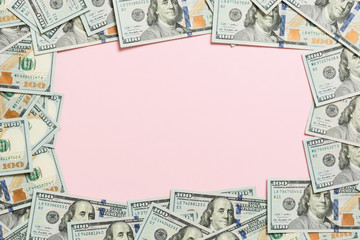 Frame made of dollars with copy space in the middle. Top view of business concept on pink background with copy space