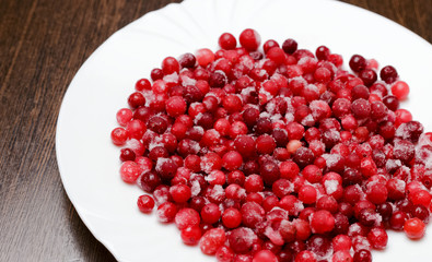 Freshly frozen ripe cranberries or red currants on a white plate. Healthy diet