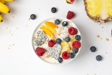 Healthy breakfast Smoothie bowl with mango, pineapple, dragon fruit, blueberries, raspberries and coconut. Tasty summer breakfast.