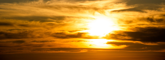 Horizontal background with setting sun through the clouds
