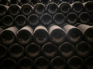Dusty old wine bottles stacked together in a wine cellar