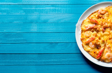 Seafood pizza with shrimp, Mussels, Crab Sticks and Hokkaido Cheese, Isolated on white plate, Top view on the blue wood texture with natural patterns background with naturday light  in summer.
