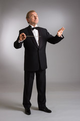 Portrait of the orchestra conductor emotionally gesticulating on a light background.