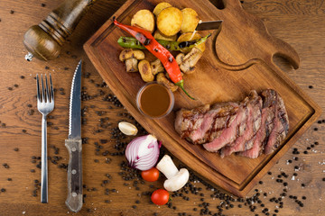 Sliced grilled steak roastbeef and onion on wooden cutting board background