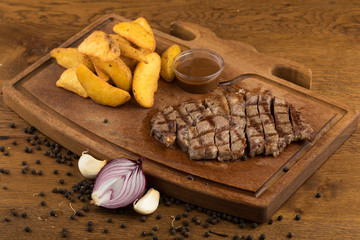 Sliced grilled steak roastbeef and onion on wooden cutting board background