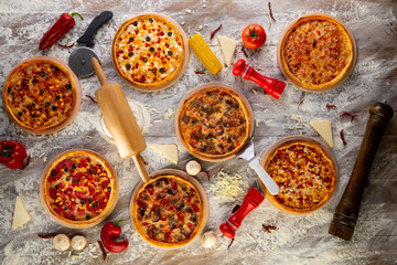 Pizza party dinner. Flat-lay of various kinds of Italian pizza over rustic wooden table, top view. Fast food lunch, celebration, gathering concept