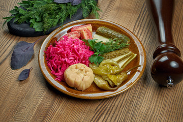 Vegetarian salad (set) of pickled vegetables - tomato, cabbage, hot pepper, garlic in a ceramic plate. Traditional Ukrainian pickles. Close up