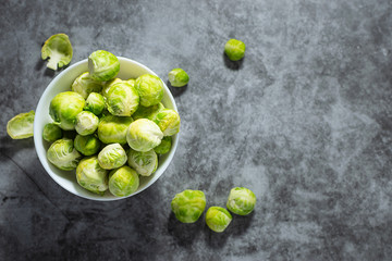 Fresh organic raw Brussels sprouts on dark stone table top view. Healthy food concept.