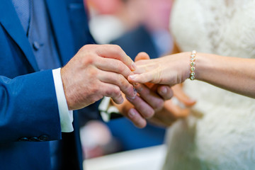 Obraz na płótnie Canvas The groom passing the wedding ring around the bride's finger