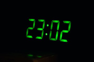 Green numbers on electronic watch in dark, midnight