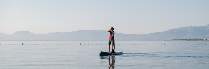 Young man paddling on sup board