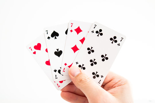 Play cards full set of sevens spread out held in hand by Caucasian male hand
