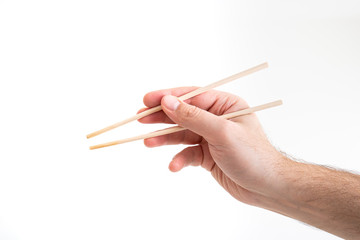 Asian chop sticks held by Caucasian male hand close up shot isolated on white