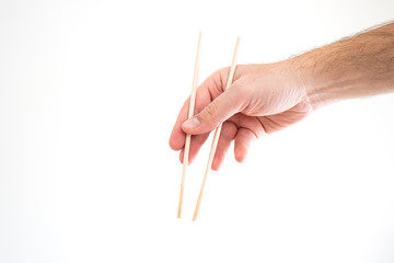 Asian chop sticks held by Caucasian male hand close up shot isolated on white