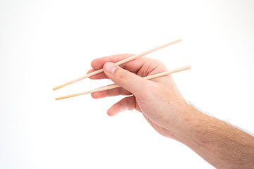 Asian chop sticks held by Caucasian male hand close up shot isolated on white