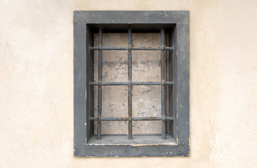 window with bars in the old city. there is one window on the wall which is closed and with a strong grating. prison in the city