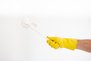 White Caucasian male hand with yellow latex glove holding a white toilet brush isolated against white background