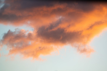 Intensely colored puffy clouds at sunset with yellows blue and pinks set against clear sky