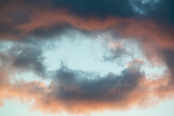 Obraz premium Intensely colored puffy clouds at sunset with yellows blue and pinks set against clear sky