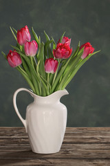 beautiful tulips in white jug on dark background