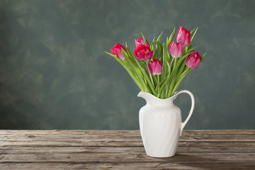 beautiful tulips in white jug on dark background